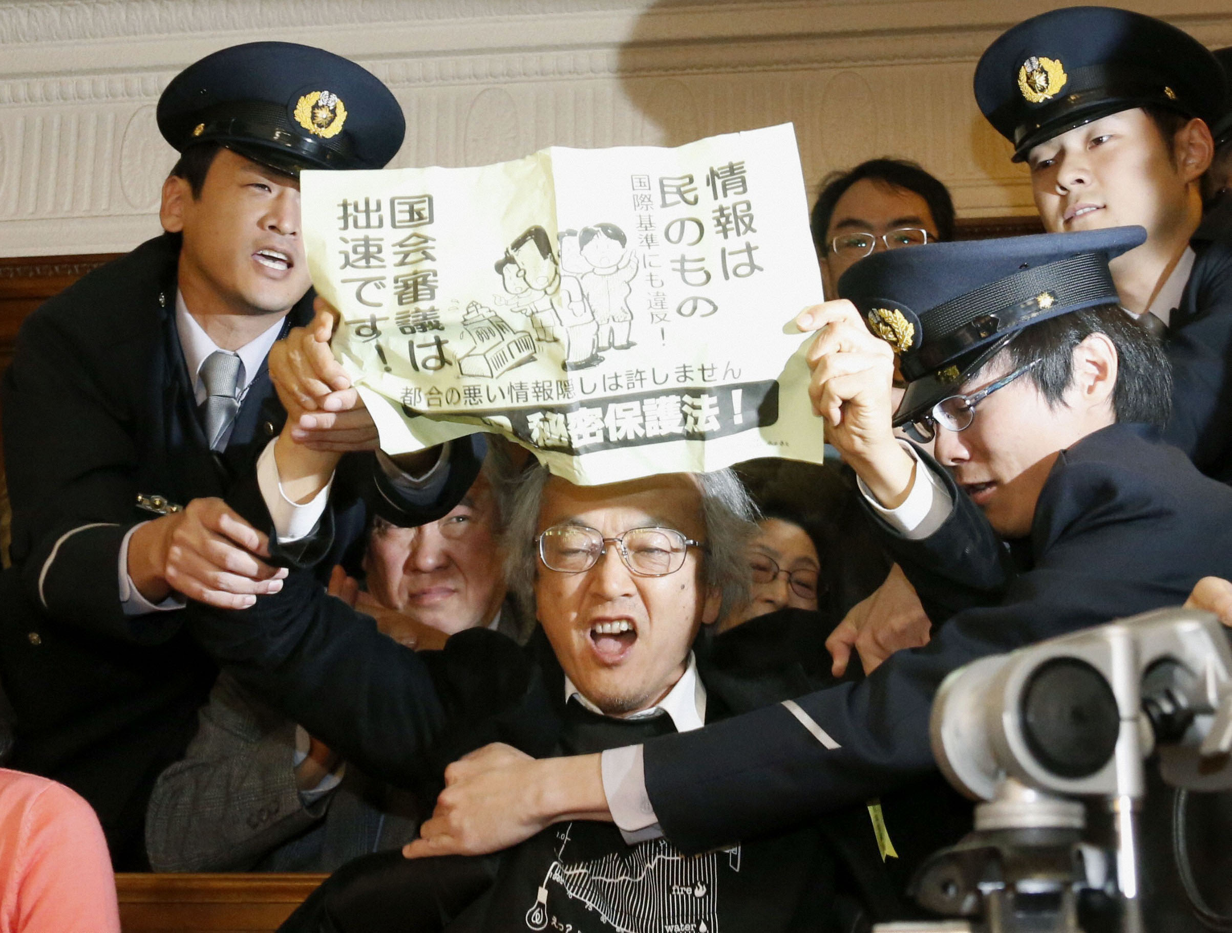 Paper trail: Guards at the Diet building restrain a man who opposes the ruling coalition's moves to force its contentious state secrets bill through the Lower House on Tuesday. | KYODO