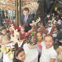 Christmas spirit: Children from Nishimachi International School in Tokyo wearing reindeer antlers show off a Christmas wreath they made Thursday at the Grand Hyatt Tokyo in Minato Ward as the hotel\'s general manager, Christophe Lorvo, looks on. | YOSHIAKI MIURA