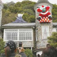 Up on the housetop: Visitors to the Uroko Museum of Art, a converted home in a Kobe district packed with Western-style residences, known as \"ijinkan,\" take photos of a mock Mount Fuji and Santa Claus on Wednesday. | KYODO