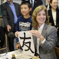 Art of diplomacy: Caroline Kennedy, the new U.S. ambassador to Japan, holds up the kanji for \"friend,\" which she wrote in a calligraphy class during a visit to Mangokuura Elementary School in Ishinomaki, Miyagi Prefecture, on Monday. | AFP-JIJI