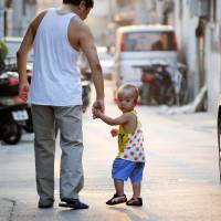 Parental policy: A father and son make their way along a Beijing street in September 2012. China\'s communist rulers announced an easing of the controversial \"one-child\" policy amid a raft of sweeping pledges unveiled Friday. | AFP-JIJI