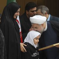 Atomic reaction?: Iranian President Hassan Rouhani kisses the daughter of a nuclear researcher who was assassinated in July 2011 during a news briefing in Tehran on Sunday. | AP