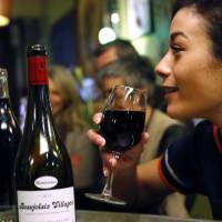 Sensational taste: A woman enjoys a glass of Beaujolais Nouveau in Lille, France, on Thursday. Beaujolais makers aim higher