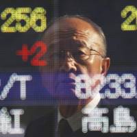 Speculation: A man is reflected in the window covering an electronic stock board at a securities firm in Tokyo on Thursday. | AP