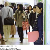 Manhunt: A policewoman (right) stands guard near the entrance of JR Funabashi Station in Chiba Prefecture. | KYODO