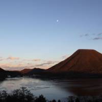 Moon view: Earth\'s satellite takes shape at dusk over Lake Haruna and conical 1,449- meter Mount Haruna-fuji. | WES LANG