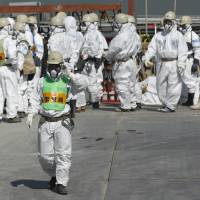 Hazmat-only: Workers mass near the reactor 4 building at Tokyo Electric Power Co.\'s Fukushima No.1 nuclear power plant in March. | BLOOMBERG