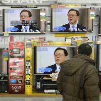 Passing the torch: A man passes by rows of televisions on display airing news broadcasts about the resignation of Tokyo Gov. Naoki Inose on Thursday at a home appliance store in Minato Ward, Tokyo. | KYODO