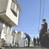 Cold case: Metropolitan Police Department investigators offer prayers Monday outside the home of a family of four slain in December 2000 in their home in Setagaya Ward, Tokyo. The case remains unsolved. | KYODO