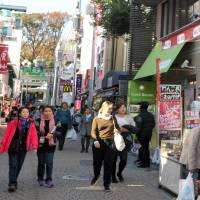 Out with the old: A recent view of Takeshita-dori shows no trace of the old stores that stood there decades ago, but the trees at Meiji Shrine are still there. | YOSHIAKI MIURA