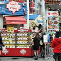 Power of the purse: Women look at samples in the showcase in front of Marion Crepes, one of the shops targeting young women, the prime movers in today\'s Takeshita-dori in the Harajuku district. | YOSHIAKI MIURA