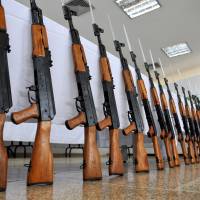 Lined up: A Colombian police officer stands guard next to AK-47 assault rifles seized in Cali, a major center for drug trafficking, in November 2009. | AFP-JIJI