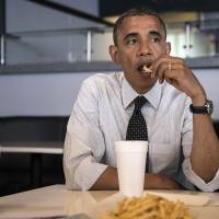 Social nosher: U.S. President Barack Obama eats a french fry while meeting with supporters about voter registration in September 2012 in Miami. | AFP-JIJI