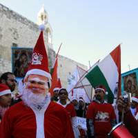 Stars of Bethlehem: Asian Christians in Santa Claus costumes march to the Church of the Nativity in Bethlehem, revered as the site of Jesus Christ\'s birth, on Wednesday. | AFP-JIJI