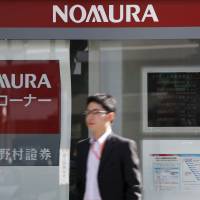 On the outside: A man passes a Nomura Securities Co. branch in Tokyo in October. | BLOOMBERG
