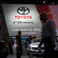 Venture offering: Visitors walk past the GAC Toyota Motor Co. booth at the Wuhan Motor Show 2013 in China in October. | BLOOMBERG