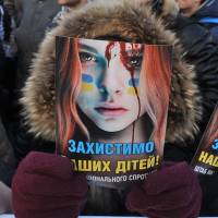 Protecting their interests: A protester holds up a poster criticizing police violence, reading \"Protect our Children,\" during a rally in front of the Ukrainian parliament in Kiev on Tuesday. | AFP-JIJI