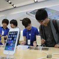 All-in-one: Staff explain the iPhone to customers at an Apple Inc. outlet in Tokyo. | BLOOMBERG