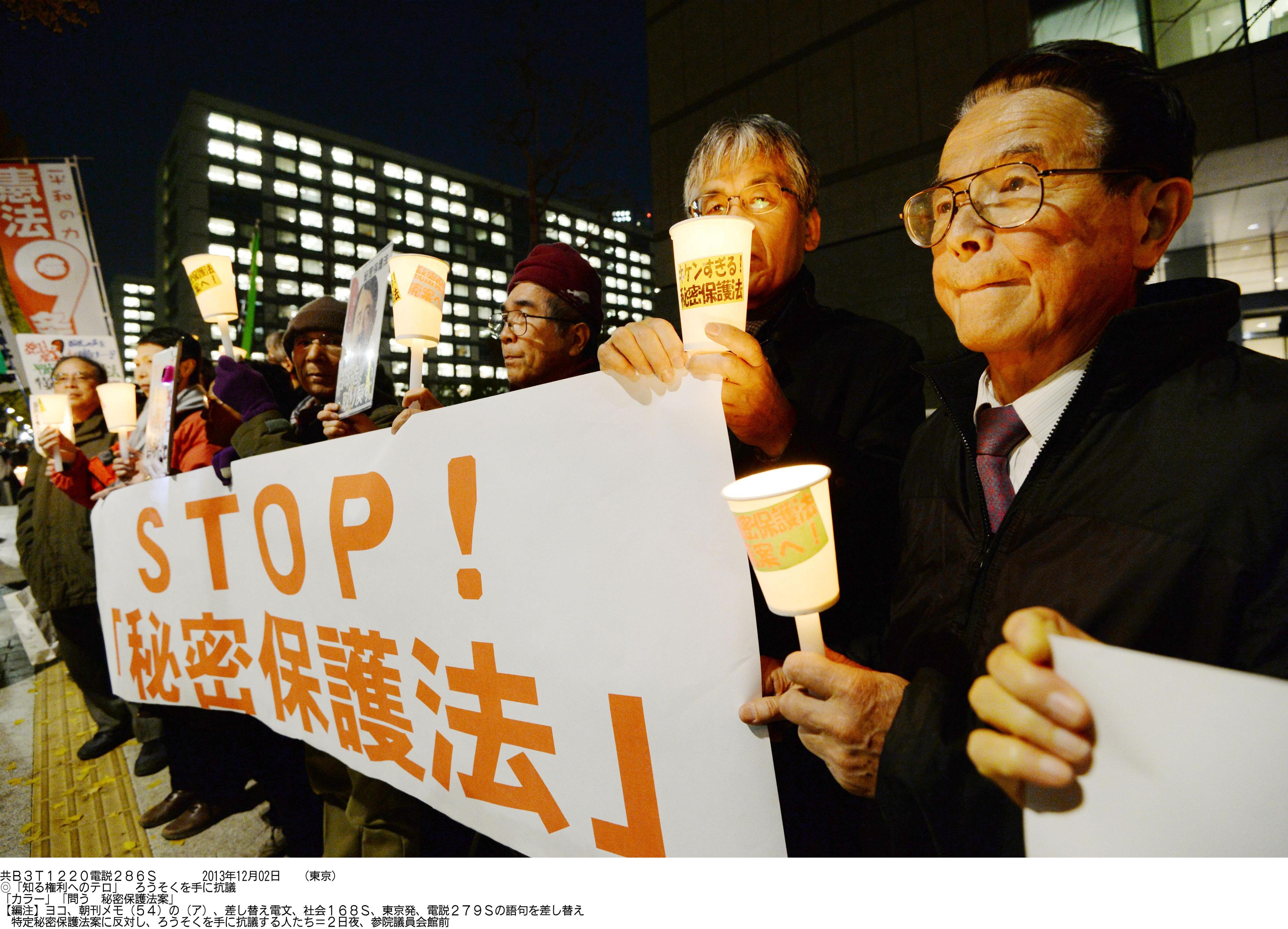Fighting the law: Demonstrators hold candles and signs at the Diet on Monday during a protest against the state secrets bill being deliberated in the Upper House. | KYODO