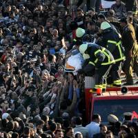 Militant attack: A funeral procession is held after a car bomb tore through a police headquarters in the Nile Delta city of Mansoura, 110 km north of Cairo, killing 11 policemen and four civilians Tuesday. It was the deadliest bombing yet in a monthslong wave of violence in Egypt blamed on Islamic militants. | AP
