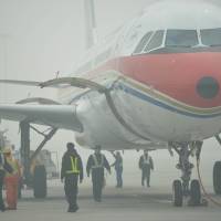 Choking on success: The ground crew works in thick smog on the tarmac of Hongqiao airport in Shanghai as severe pollution blanketed the city Friday. The city’s PM2.5 levels had soared to a density of 468 micrograms per cubic meter by midnight — more than 10 times the level deemed safe by the World Health Organization, state media said. Smog at extremely hazardous levels in Shanghai