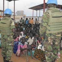Peace eludes: United Nations soldiers stand guard as civilians gather at the compound of the U.N. Mission in the Republic of South Sudan (UNMISS), adjacent to Juba International Airport, to take refuge Wednesday amid spreading armed clashes among military factions. Soldiers defect as South Sudan ethnic violence spreads