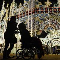 Visitors to the Kobe Luminarie are silhouetted Tuesday evening during a special showing for guests with physical disabilities. The annual light show to remember the city\'s 1995 quake officially begins Thursday and runs through Dec. 16. | KYODO