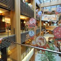 Nine huge \"ema\" wooden plaques requesting good health and success in business during 2014 hang as New Year decorations in the atrium at the Tokyo Midtown office and shopping complex in Roppongi, Tokyo, on Friday. | YOSHIAKI MIURA