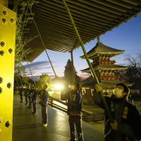 Priests and workers at Naritasan Shinshoji Temple in Chiba Prefecture carry out an annual cleaning ritual for year\'s end at dawn Friday using approximately 10-meter-long bamboo brooms. | KYODO