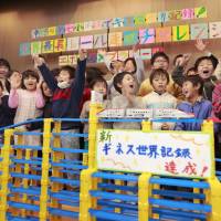Pupils at Takinogawa No. 7 Elementary School in Tokyo celebrate Sunday at an event hosted by Panasonic Corp. after their attempt to run a toy train, powered by a single Panasonic Evolta AA battery, broke a Guiness world record by traveling 5.6 km along a multilevel track before running out of power. The previous record was 4 km. | KYODO
