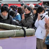 After dropping monetary offerings into a large container at the shrine entrance, visitors make silent prayers.  | YOSHIAKI MIURA