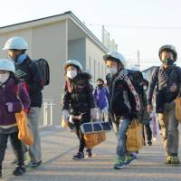 Taking precautions: Children in Hamamatsu, Shizuoka Prefecture, walk to their elementary school, which reopened Wednesday after being closed due to a mass norovirus outbreak. | KYODO