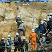 Digging deep: Experts from the Nuclear Regulation Authority examine the soil around reactor 2 at Tsuruga nuclear power plant in Fukui Prefecture on Monday. | KYODO