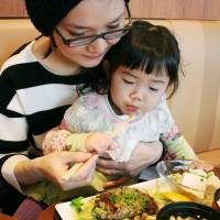 Eating green: A mother and daughter try a hamburger dish containing euglena at a restaurant in Shinagawa Ward, Tokyo, in December. | KYODO