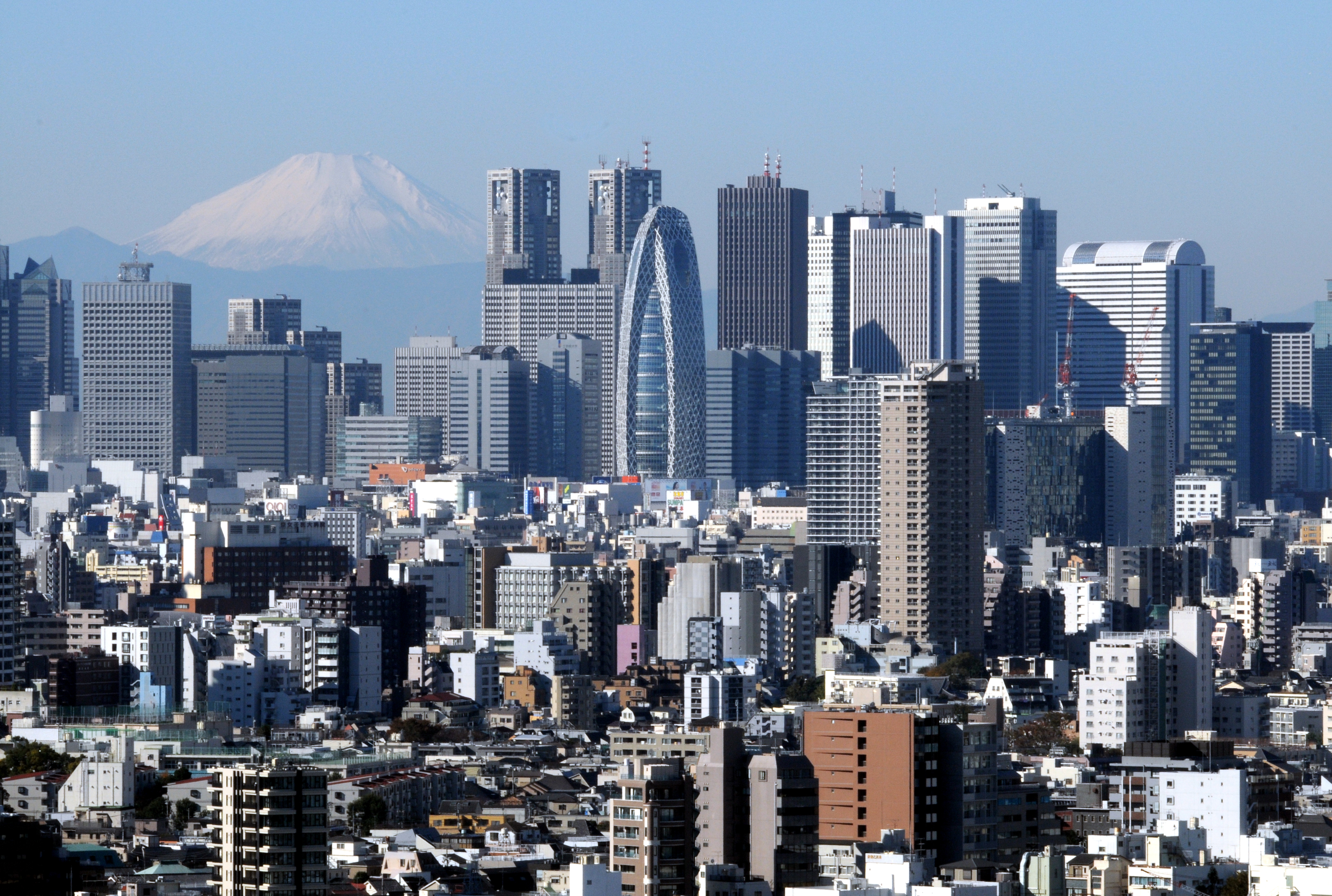 Concrete peaks: Mount Fuji, shown in December, provides a dramatic backdrop for the twin towers of City Hall and the dozens of other skyscrapers that have been erected on the west side of Shinjuku Station since the war. | SATOKO KAWASAKI