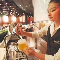Last call: A bartender pours a glass of Heartland beer in the Heartland bar at the Roppongi Hills complex in Tokyo last April. The bar effectively closed Monday. | BLOOMBERG