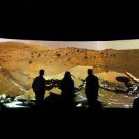 Mission to Mars: People look at the \"Mars Window,\" a projection of images taken by NASA\'s Mars Curiosity Rover at at The National Maritime Museum in Greenwich, London, last June.  | AP