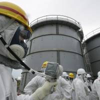 Suit up: An Tokyo Electric Power Co. official measures radiation levels where radioactive water leaked from a storage tank in August, at the Fukushima No. 1 nuclear power plant in Okuma, Fukushima Prefecture on Nov. 7. | AP