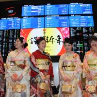 Brokerage employees in kimono pose in front of the quotation board at the Tokyo Stock Exchange on Monday, the first trading day of the year. | SATOKO KAWASAKI