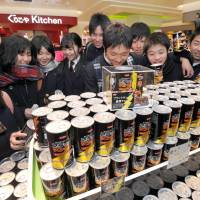 High school students gather around a display of Black Thunder chocolates at a temporary Yuraku Confectionery Co. shop at Tokyo Station on Wednesday. The chocolate is a popular \"giri\" (obligatory) gift given by many women on St. Valentine\'s Day to men as a courtesy. | YOSHIAKI MIURA