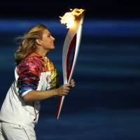 Russian tennis player Maria Sharapova carries the Olympic torch during the 2014 Winter Olympics opening ceremony. | AP