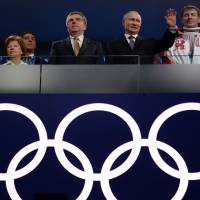 International Olympic Committee President Thomas Bach stands next to Russian President Vladimir Putin as he waves during the closing ceremony of the 2014 Winter Olympics. | AFP-JIJI