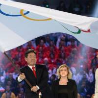 Lee Seok-rae, the Mayor of  Pyeongchang, South Korea, holds the Olympic flag during the closing ceremony of the 2014 Winter Olympics. | AFP-JIJI