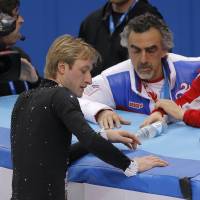 Hometown hero Evgeni Plushenko speaks with his coach Alexei Mishin ( right) and other team members before pulling out of the competition. | AP