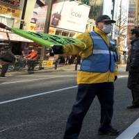 Ever alert: A guard watches over the vehicle-free promenade in Tokyo\'s Akihabara district on Jan. 12. | YOSHIAKI MIURA