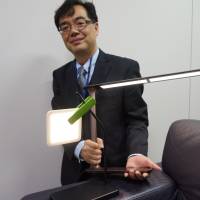 Sleek design: Yasuki Kawashima of NEC Lighting Ltd. shows off an OLED desk lamp. | KAZUAKI NAGATA