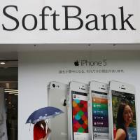 Talk is cheap: A passer-by chats on her mobile phone in front of a SoftBank store in Tokyo last July. Local startup SoftBank on course to become global player