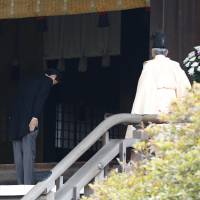 Prime Minister Shinzo Abe bows beside a Shinto priest as he visits war-related Yasukuni Shrine in Tokyo on Dec. 26. Abe put Japan on back foot in global PR war with China
