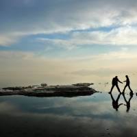 Two men walk toward salt-covered rocks that were once deep underwater at Lake Oroumieh in northwestern Iran on Saturday. Oroumieh, one of the biggest saltwater lakes on Earth, has shrunk more than 80 percent to 1,000 sq. km in the past decade, leaving ships abandoned and rotting in solidified salt. Saving lake is top priority for Iran's Rouhani