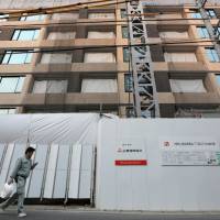 High-riser: A worker walks past the Parkhouse Grand Minamiaoyama Takagicho residential building being developed by a unit of Mitsubishi Estate Co. in Tokyo on Monday. | BLOOMBERG